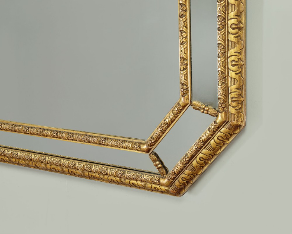 An octagonal gilded cushion frame mirror featuring floral embossed moulding and bevelled mirror inserts around a central glass plate. View VII