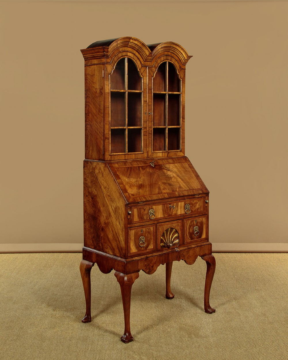 A Queen Anne style walnut bureau bookcase featuring a double-domed top, glazed upper doors, a slant-front writing slope, lower drawers with a carved shell motif, and slender cabriole legs. View IV