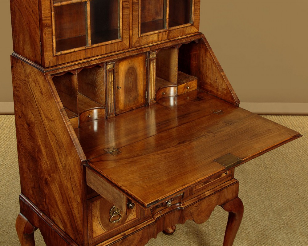 A Queen Anne style walnut bureau bookcase featuring a double-domed top, glazed upper doors, a slant-front writing slope, lower drawers with a carved shell motif, and slender cabriole legs. View VIII