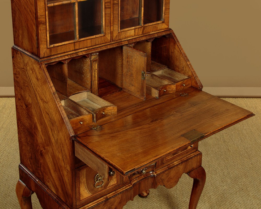 A Queen Anne style walnut bureau bookcase featuring a double-domed top, glazed upper doors, a slant-front writing slope, lower drawers with a carved shell motif, and slender cabriole legs. View IX