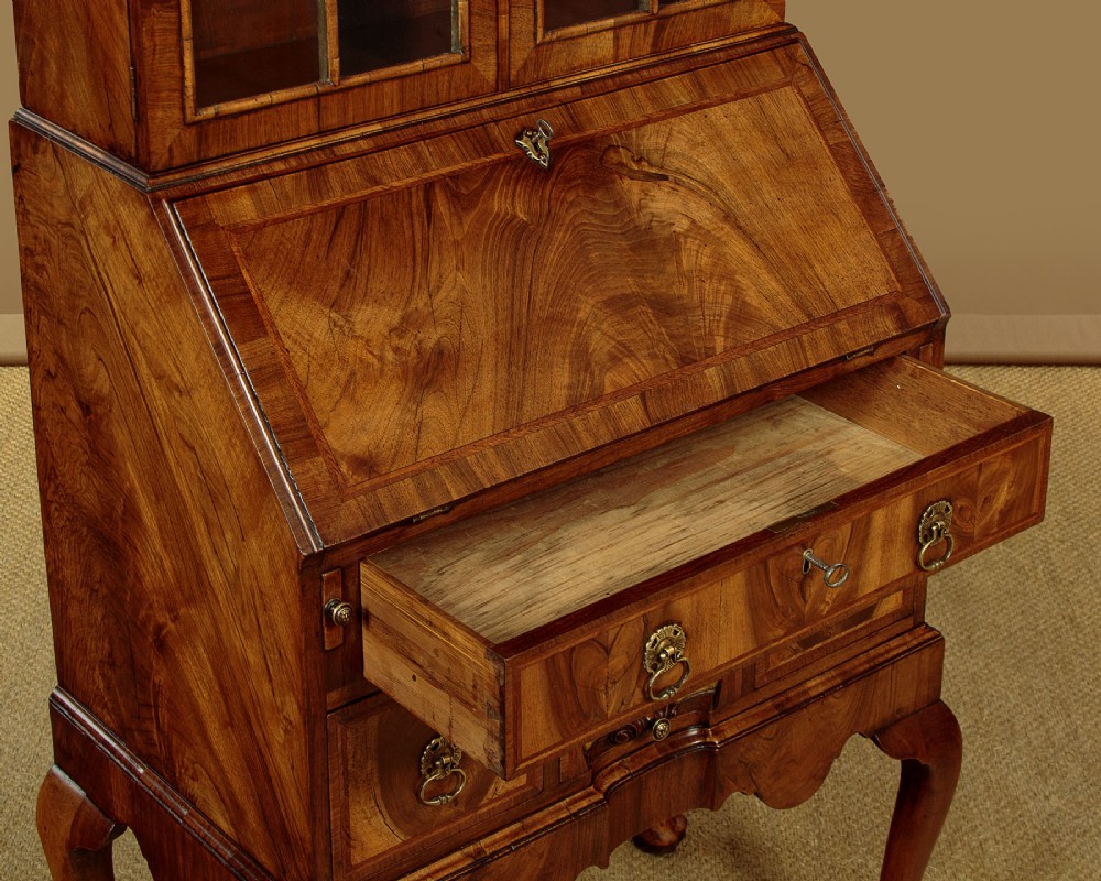 A Queen Anne style walnut bureau bookcase featuring a double-domed top, glazed upper doors, a slant-front writing slope, lower drawers with a carved shell motif, and slender cabriole legs. View XI
