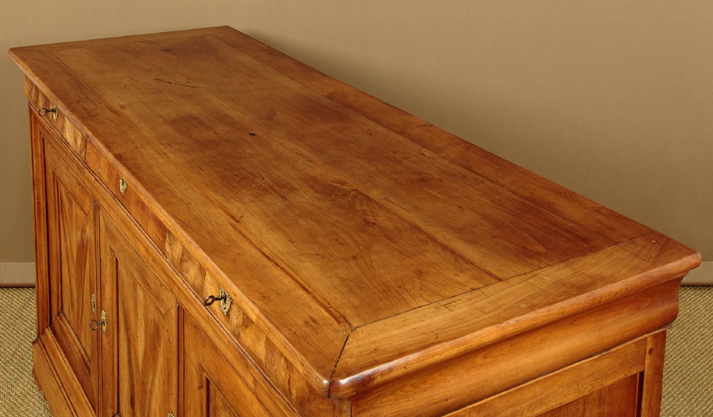 A 19th-century French cherrywood enfilade featuring three drawers over three panelled doors with geometric wood grain and brass escutcheons. View IV