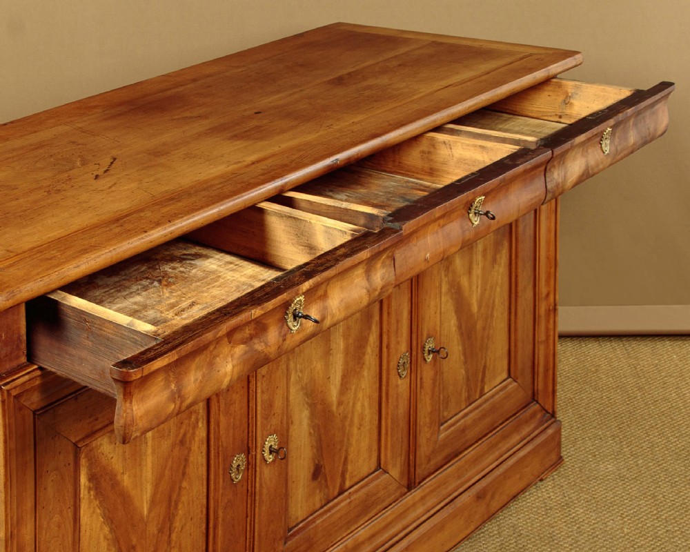A 19th-century French cherrywood enfilade featuring three drawers over three panelled doors with geometric wood grain and brass escutcheons. View VI