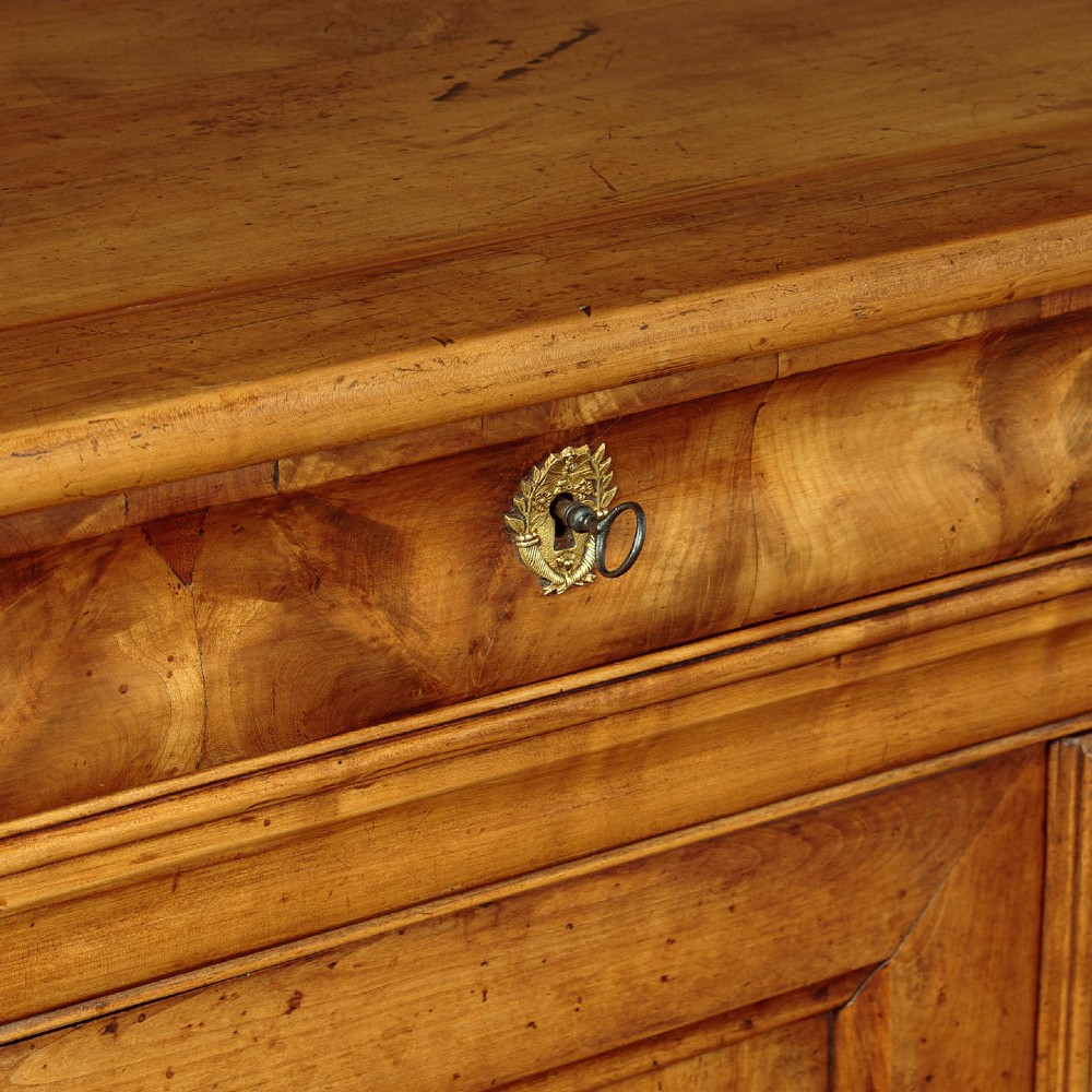 A 19th-century French cherrywood enfilade featuring three drawers over three panelled doors with geometric wood grain and brass escutcheons. View VII