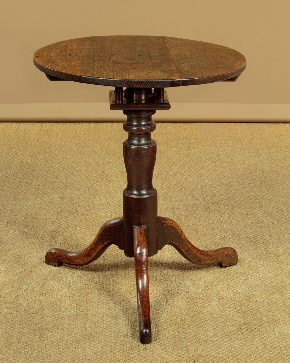 An 18th-century dark oak tripod table featuring a circular top, a central turned column, and three splayed legs.