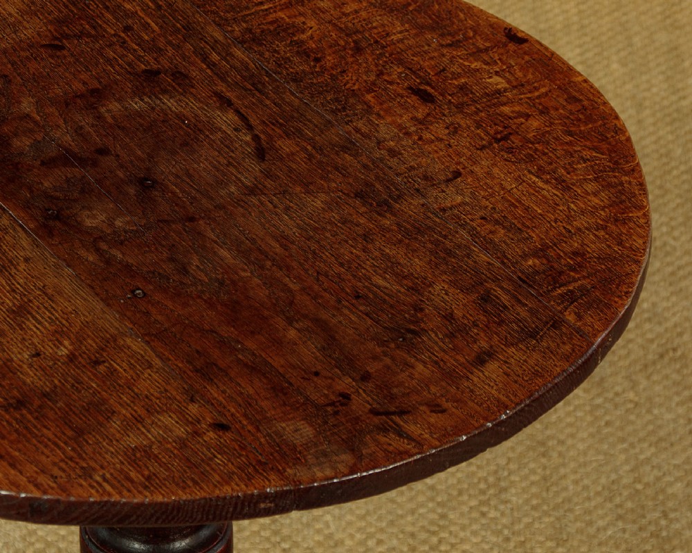 An 18th-century dark oak tripod table featuring a circular top, a central turned column, and three splayed legs. View V
