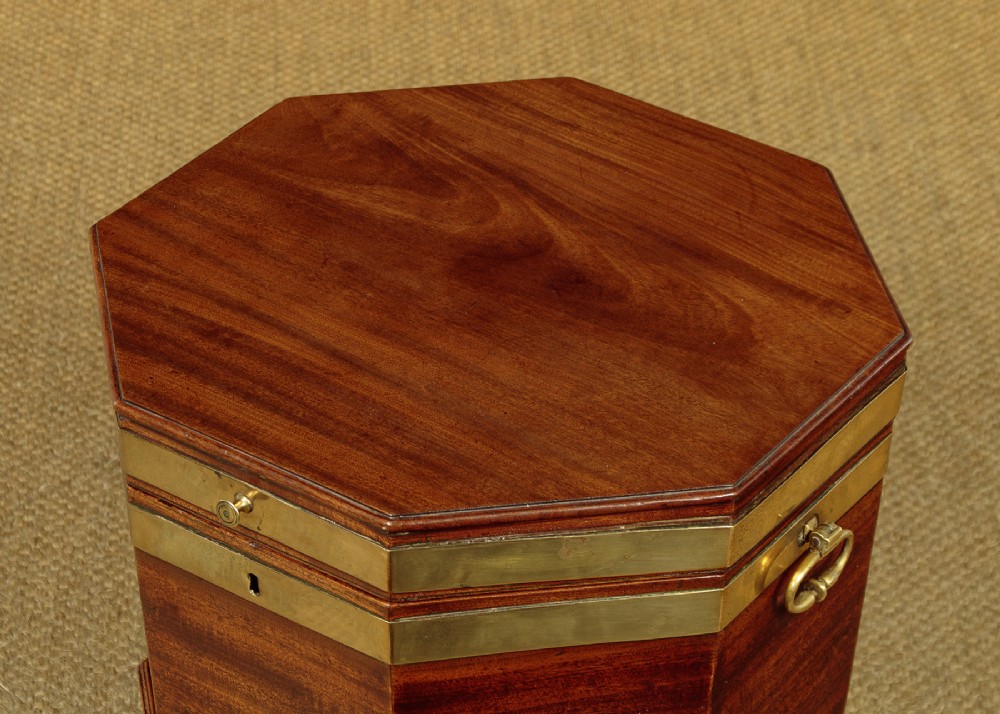 An octagonal Georgian mahogany cellarette bound in brass bands on tapered legs with castors. View III