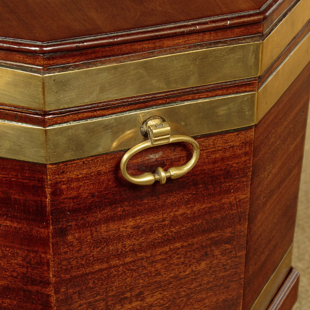 An octagonal Georgian mahogany cellarette bound in brass bands on tapered legs with castors. View VI