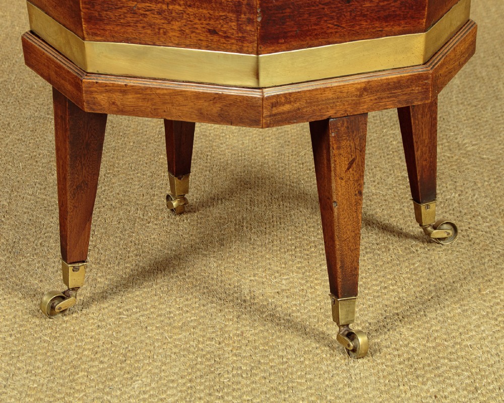 An octagonal Georgian mahogany cellarette bound in brass bands on tapered legs with castors. View VII