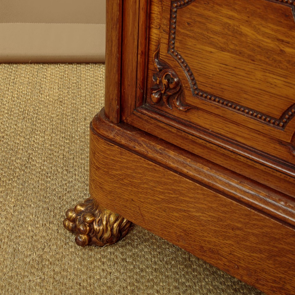 A large four-door oak bookcase featuring decorative turned spindles on the upper door sections, gilded brass frieze mounts, and carved lower timber panels. View XI