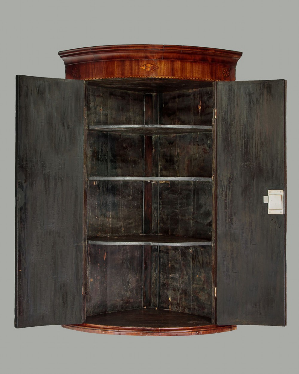 A George III bow-front mahogany corner cupboard featuring twin doors with inlaid fan motifs, crossbanded borders, and brass H-hinges. View II