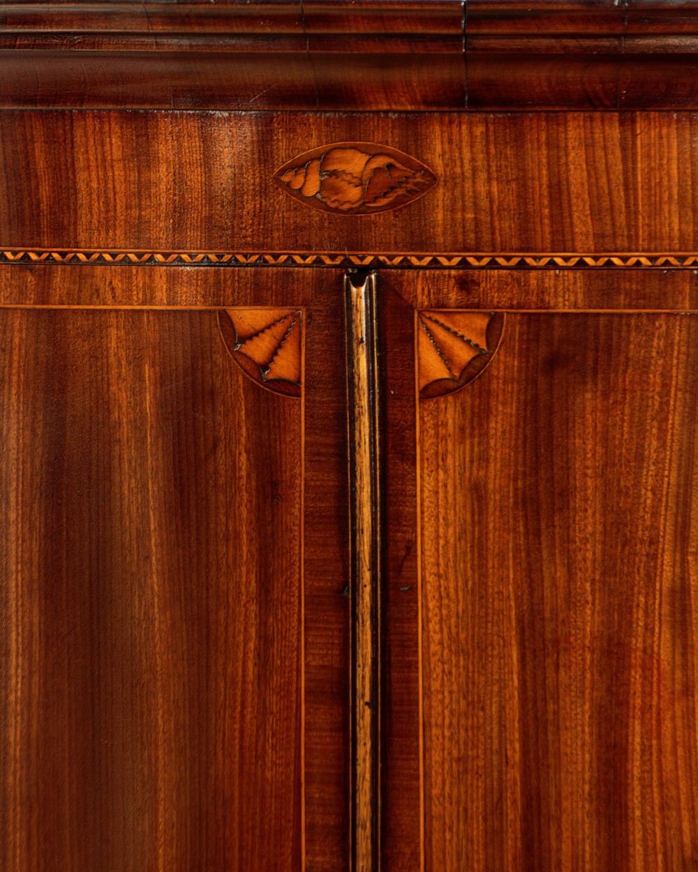 A George III bow-front mahogany corner cupboard featuring twin doors with inlaid fan motifs, crossbanded borders, and brass H-hinges. View III
