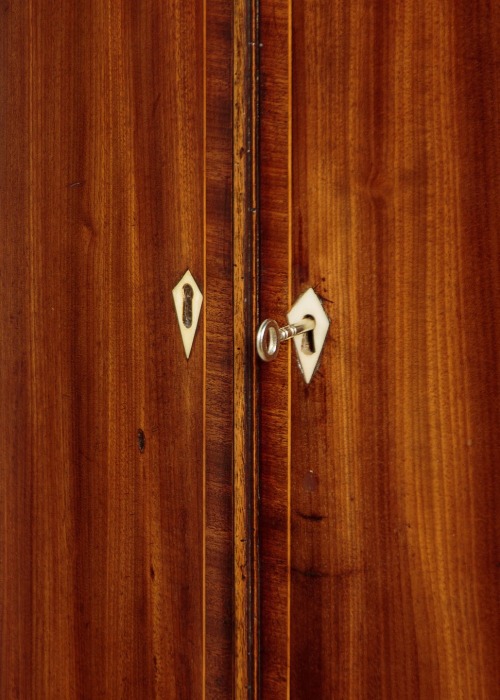 A George III bow-front mahogany corner cupboard featuring twin doors with inlaid fan motifs, crossbanded borders, and brass H-hinges. View V