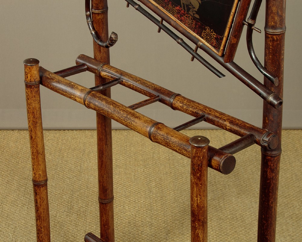 Late Victorian dark bamboo hall stand featuring a central diamond mirror, a hand-painted floral lacquer panel, coat pegs, and a stick stand base. View X