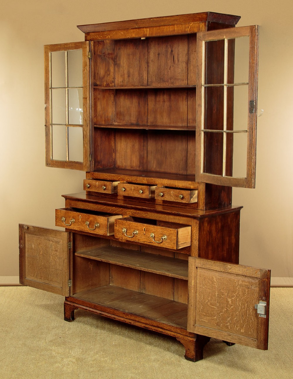 A Georgian Welsh oak cwpwrdd gwydr featuring a glazed upper section with two six-pane glass doors above three small drawers, resting on a base cabinet with two drawers over a panelled double cupboard. View III
