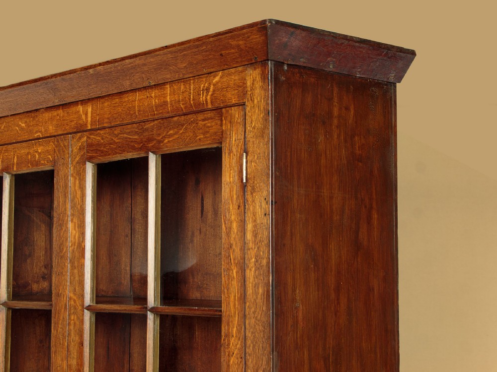 A Georgian Welsh oak cwpwrdd gwydr featuring a glazed upper section with two six-pane glass doors above three small drawers, resting on a base cabinet with two drawers over a panelled double cupboard. View IV
