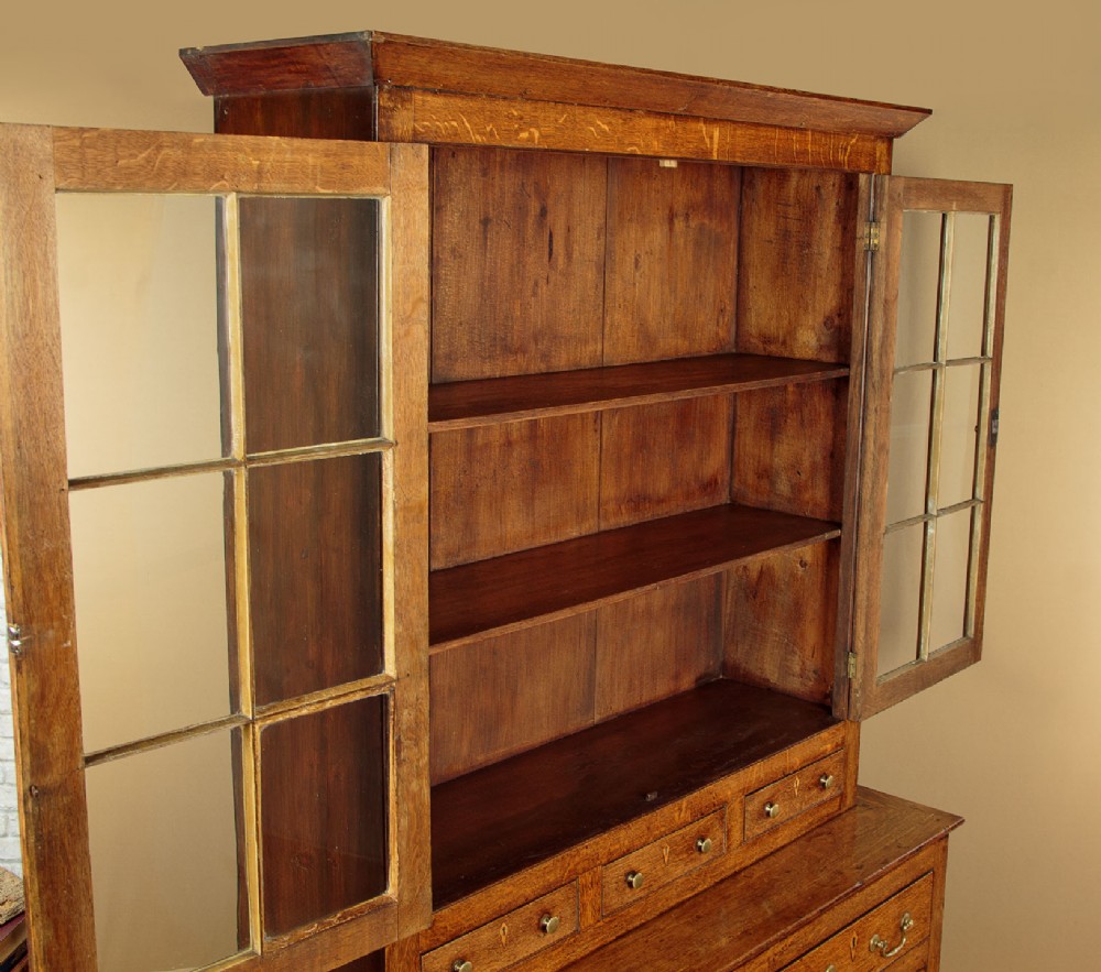 A Georgian Welsh oak cwpwrdd gwydr featuring a glazed upper section with two six-pane glass doors above three small drawers, resting on a base cabinet with two drawers over a panelled double cupboard. View V