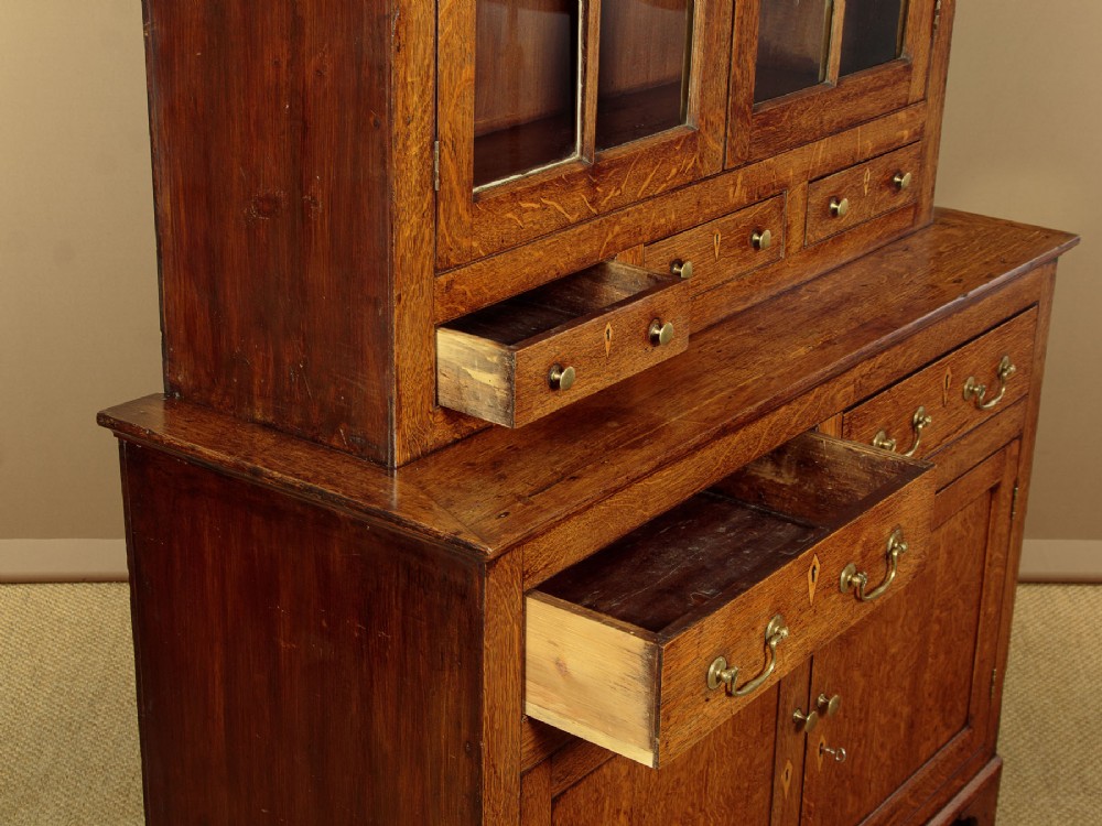 A Georgian Welsh oak cwpwrdd gwydr featuring a glazed upper section with two six-pane glass doors above three small drawers, resting on a base cabinet with two drawers over a panelled double cupboard. View VI