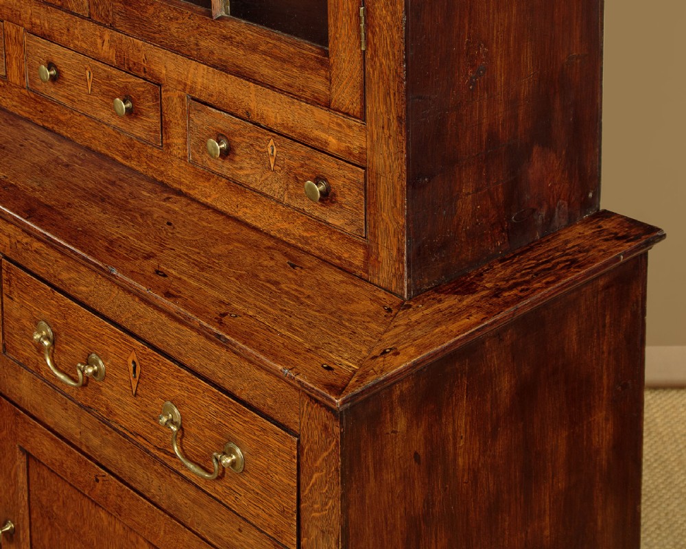 A Georgian Welsh oak cwpwrdd gwydr featuring a glazed upper section with two six-pane glass doors above three small drawers, resting on a base cabinet with two drawers over a panelled double cupboard. View VII