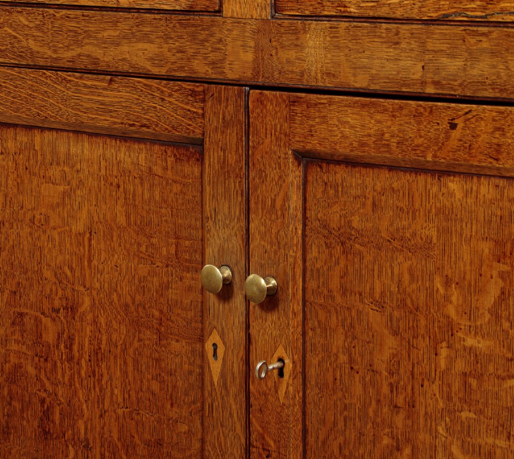 A Georgian Welsh oak cwpwrdd gwydr featuring a glazed upper section with two six-pane glass doors above three small drawers, resting on a base cabinet with two drawers over a panelled double cupboard. View IX