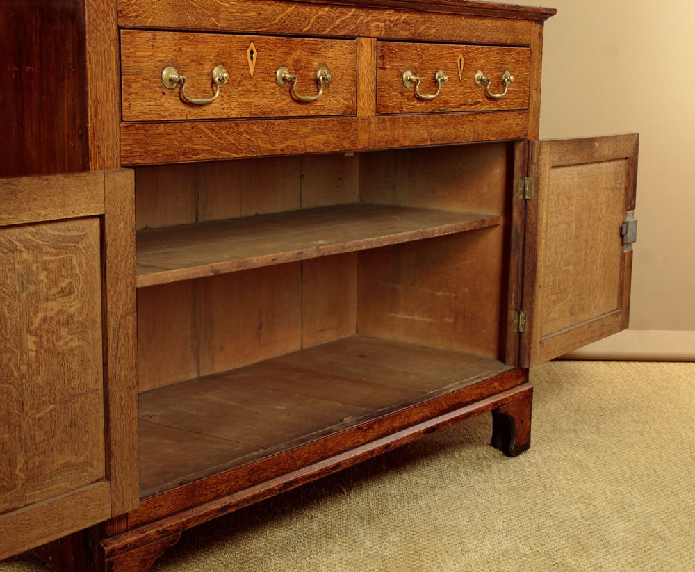 A Georgian Welsh oak cwpwrdd gwydr featuring a glazed upper section with two six-pane glass doors above three small drawers, resting on a base cabinet with two drawers over a panelled double cupboard. View X