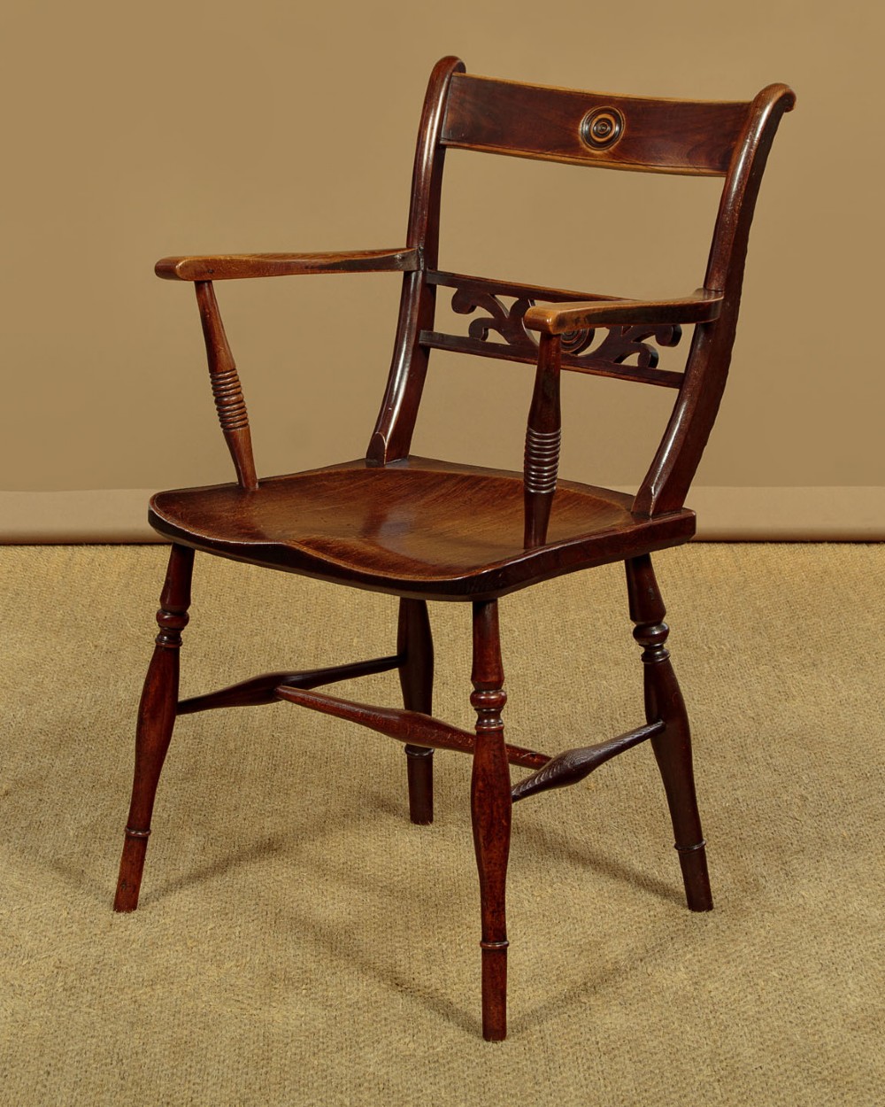 A Victorian Oxford bar back Windsor armchair made from dark timber with turned legs, a carved middle back rail, and a contoured saddle seat.