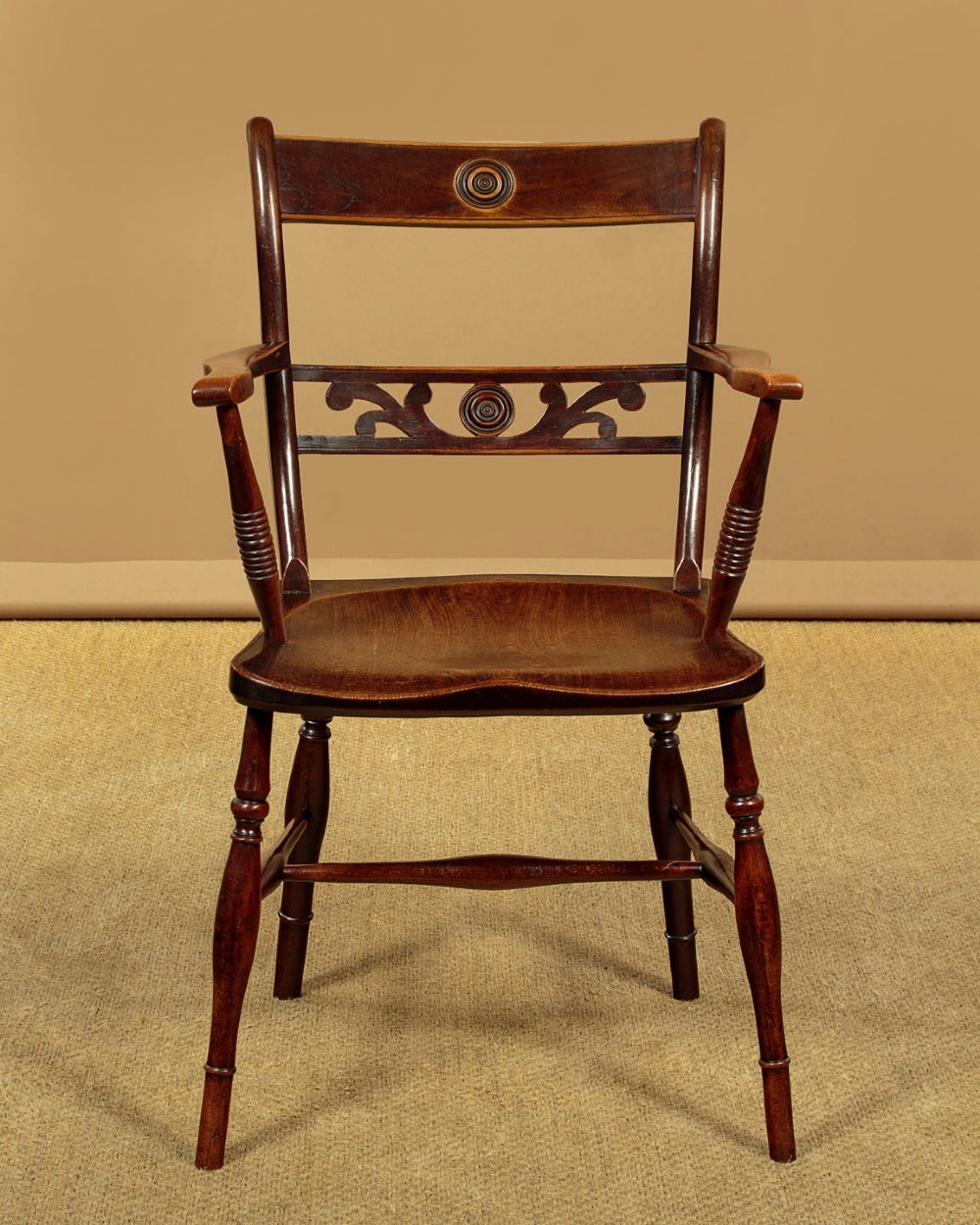 A Victorian Oxford bar back Windsor armchair made from dark timber with turned legs, a carved middle back rail, and a contoured saddle seat. View II