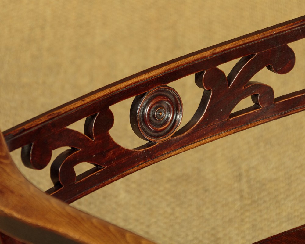 A Victorian Oxford bar back Windsor armchair made from dark timber with turned legs, a carved middle back rail, and a contoured saddle seat. View VI