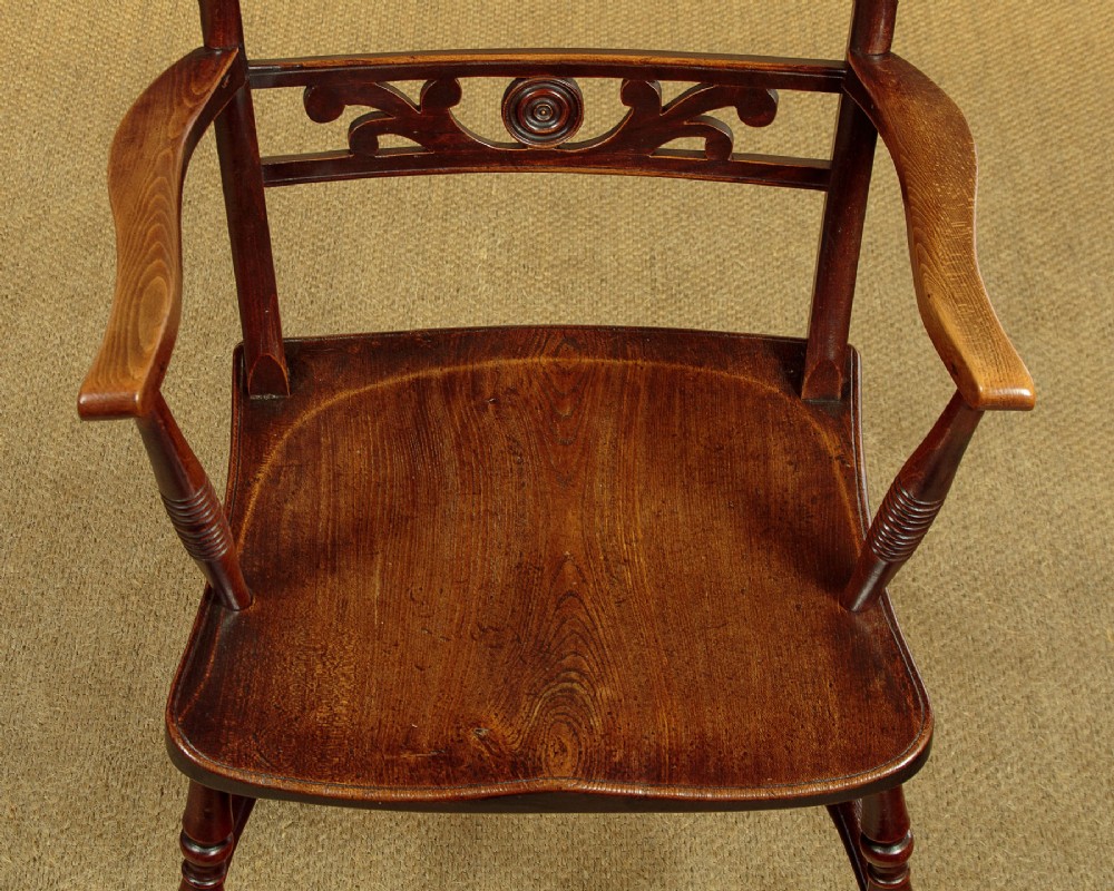 A Victorian Oxford bar back Windsor armchair made from dark timber with turned legs, a carved middle back rail, and a contoured saddle seat. View X