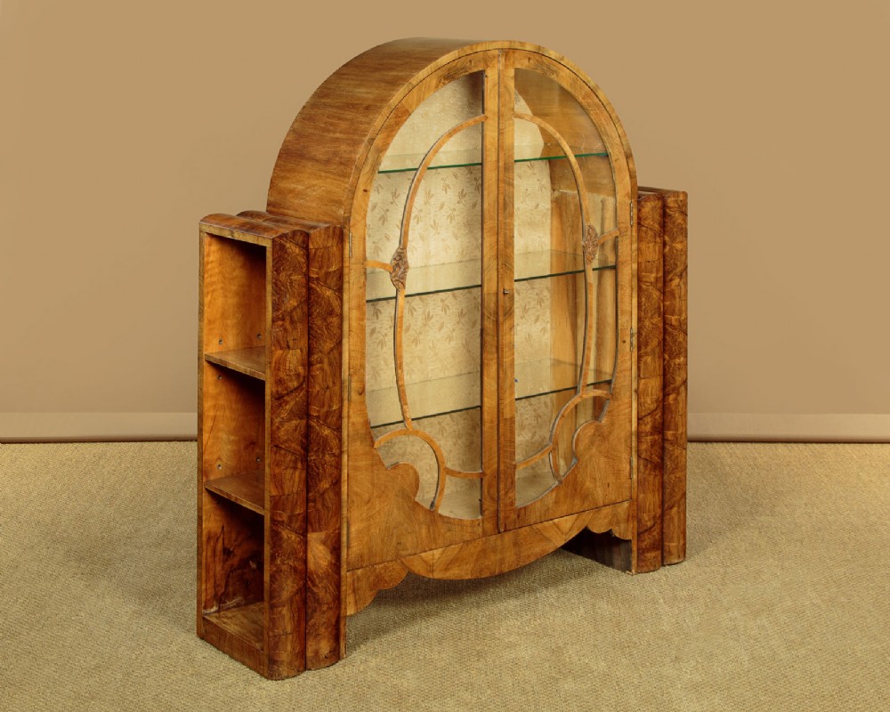 An Art Deco walnut display cabinet featuring a domed central section with two glazed doors and curved glazing bars, flanked by open side shelves.