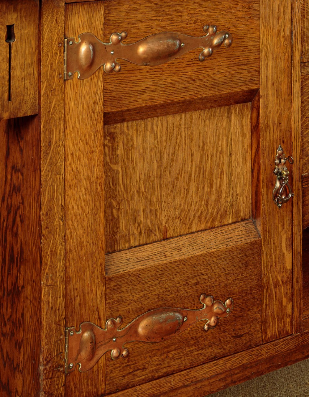 An Arts and Crafts quarter-sawn oak dresser featuring a mirrored top structure with small display shelves, inlaid floral details, hammered copper strap hinges, two drawers, and a lower cupboard. View IX