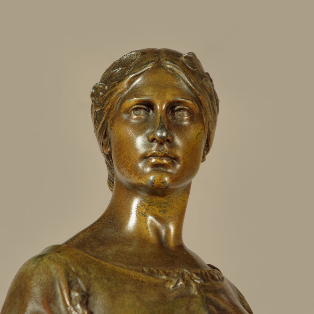 A patinated spelter statue of a standing female figure titled Dignite holding a sword and foliage branch, mounted on an integral square base. View VI