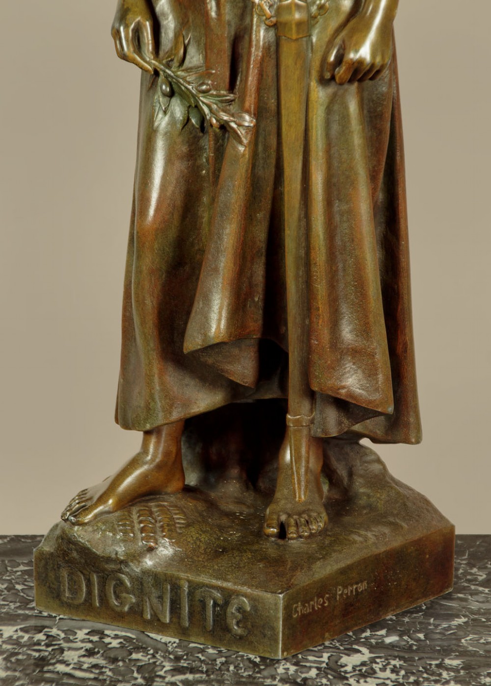 A patinated spelter statue of a standing female figure titled Dignite holding a sword and foliage branch, mounted on an integral square base. View X