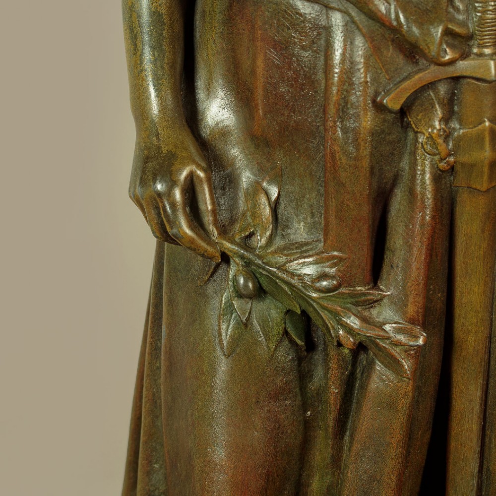 A patinated spelter statue of a standing female figure titled Dignite holding a sword and foliage branch, mounted on an integral square base. View XI