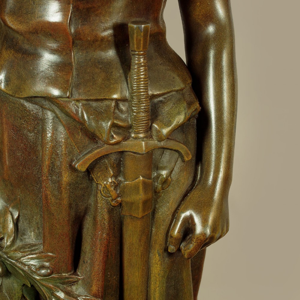 A patinated spelter statue of a standing female figure titled Dignite holding a sword and foliage branch, mounted on an integral square base. View XII