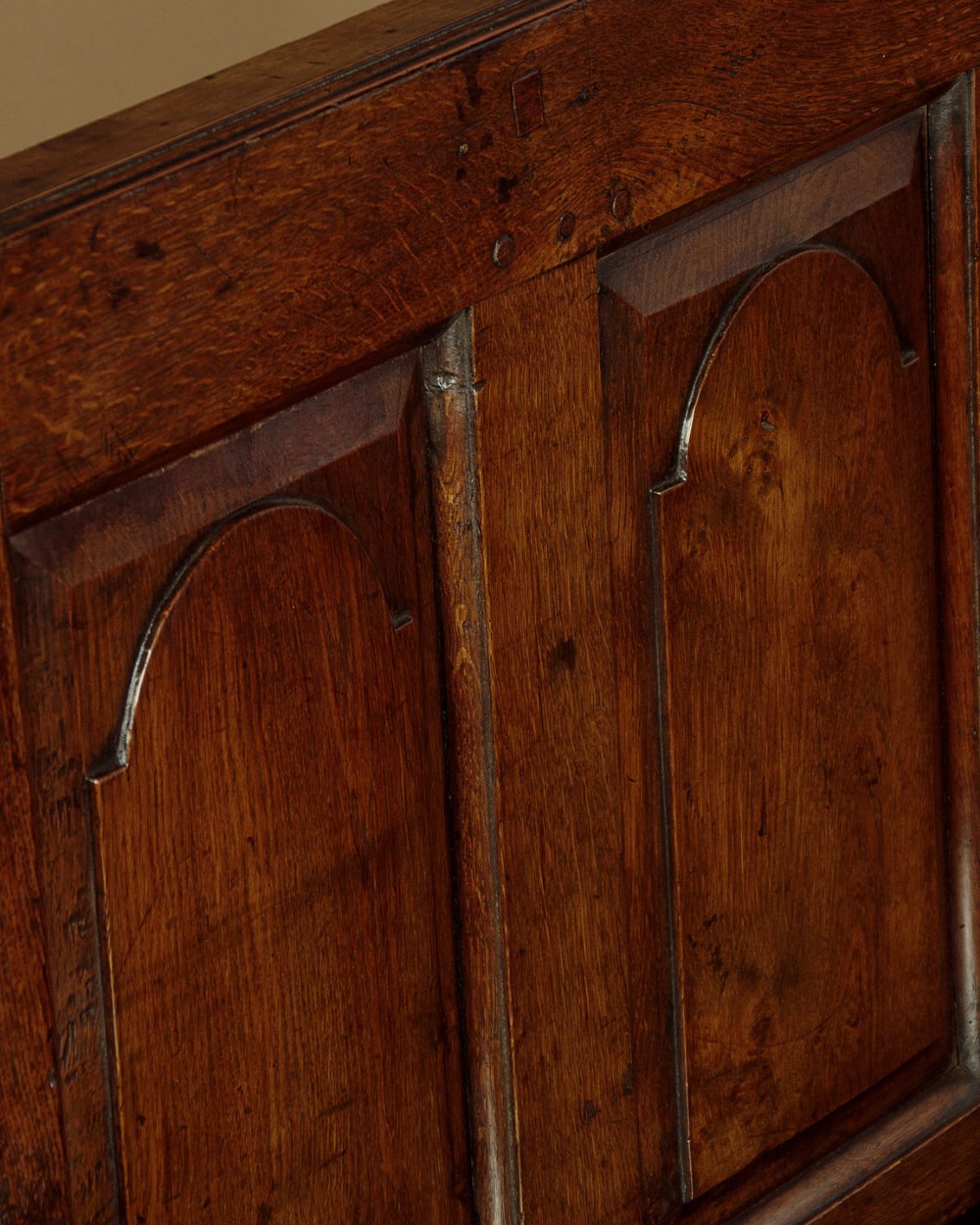 A dark oak box settle featuring a three-panel back with subtle arched top mouldings, curved armrests on turned supports, and a hinged seat opening to storage. View V