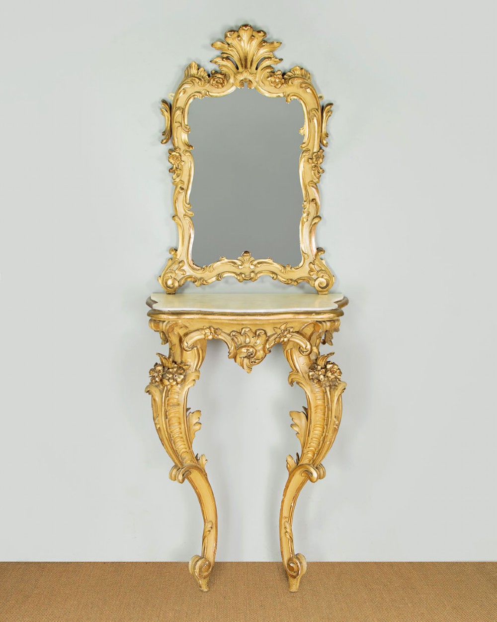 A small Rococo Revival gilded console table with a marble top, paired with an ornate matching carved wall mirror.