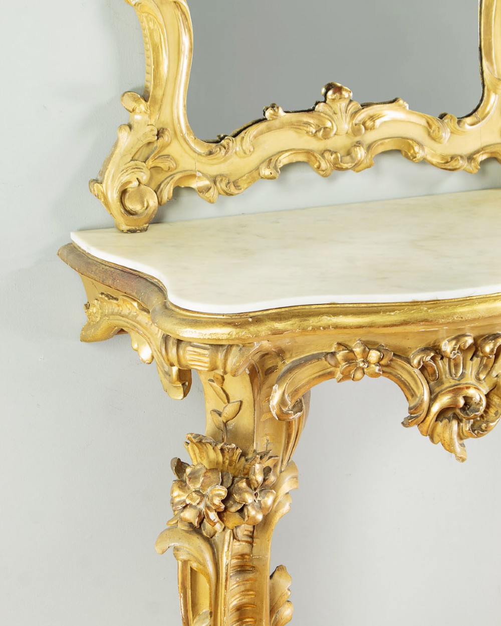 A small Rococo Revival gilded console table with a marble top, paired with an ornate matching carved wall mirror. View VII