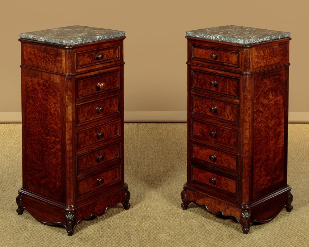 A pair of late Victorian dark rosewood and amboyna veneer tall bedside drawer pedestals featuring grey marble tops and turned wooden knobs.