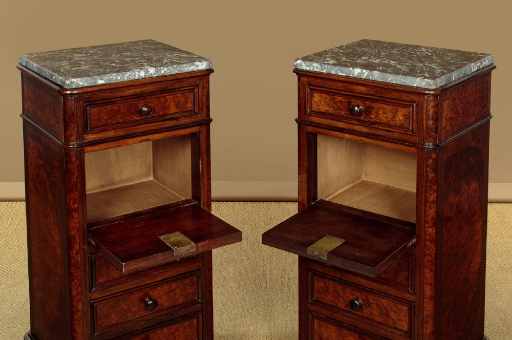 A pair of late Victorian dark rosewood and amboyna veneer tall bedside drawer pedestals featuring grey marble tops and turned wooden knobs. View V