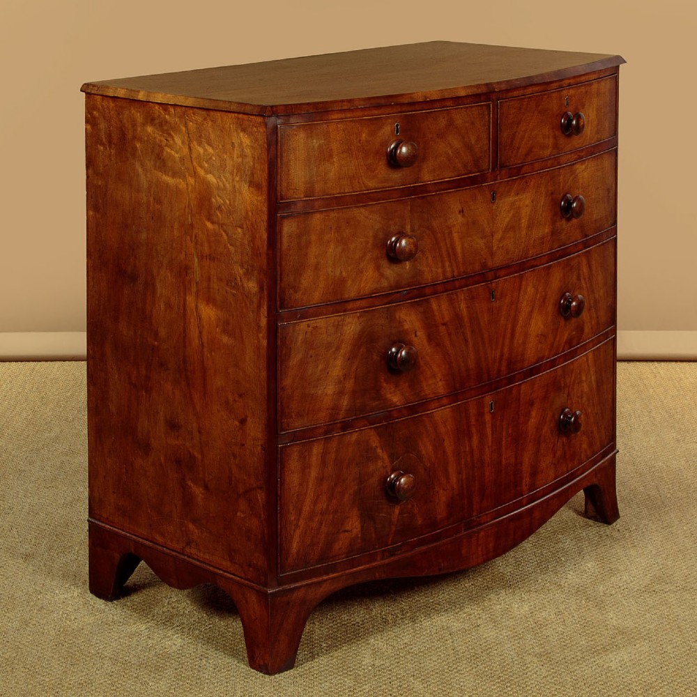 A Regency bowfront mahogany chest of drawers featuring two short and three long drawers with turned wooden knobs and a curved lower apron on splayed feet. View III