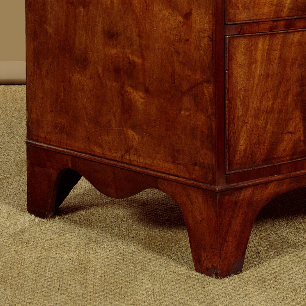 A Regency bowfront mahogany chest of drawers featuring two short and three long drawers with turned wooden knobs and a curved lower apron on splayed feet. View XII
