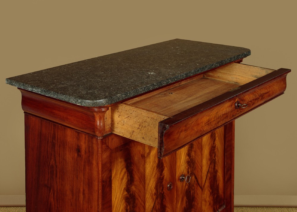 A 19th-century French Louis Philippe flame mahogany cabinet featuring a dark marble top, a frieze drawer, and four symmetrical veneered cupboard doors over a plinth base. View VI