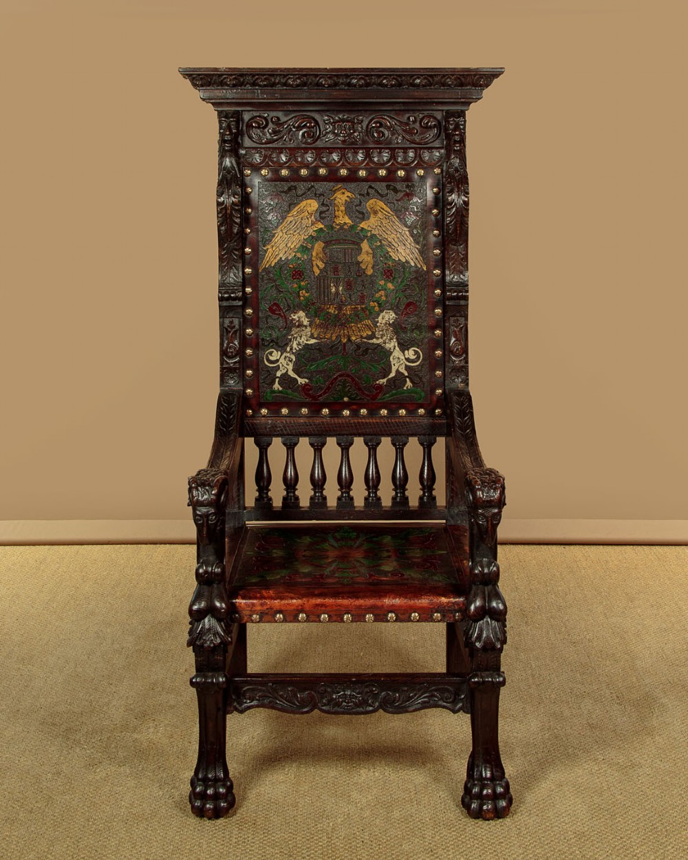 A tall, dark carved oak Renaissance Revival throne chair featuring a high back with a painted heraldic leather panel, lion head terminal armrests, and brass stud trim. View II
