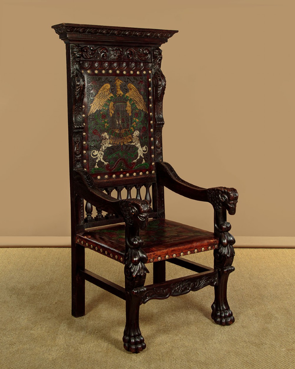 A tall, dark carved oak Renaissance Revival throne chair featuring a high back with a painted heraldic leather panel, lion head terminal armrests, and brass stud trim. View III