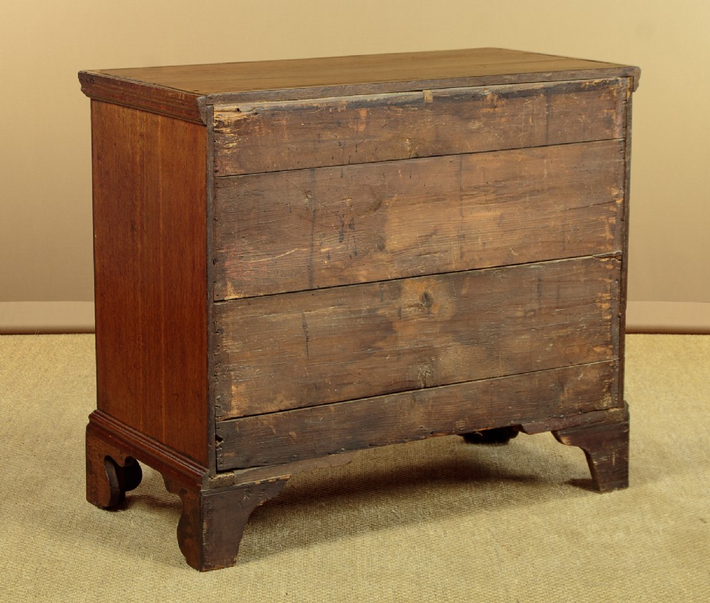 A Georgian oak chest of drawers featuring four graduated drawers with decorative pierced brass handles and bracket feet. View XIII