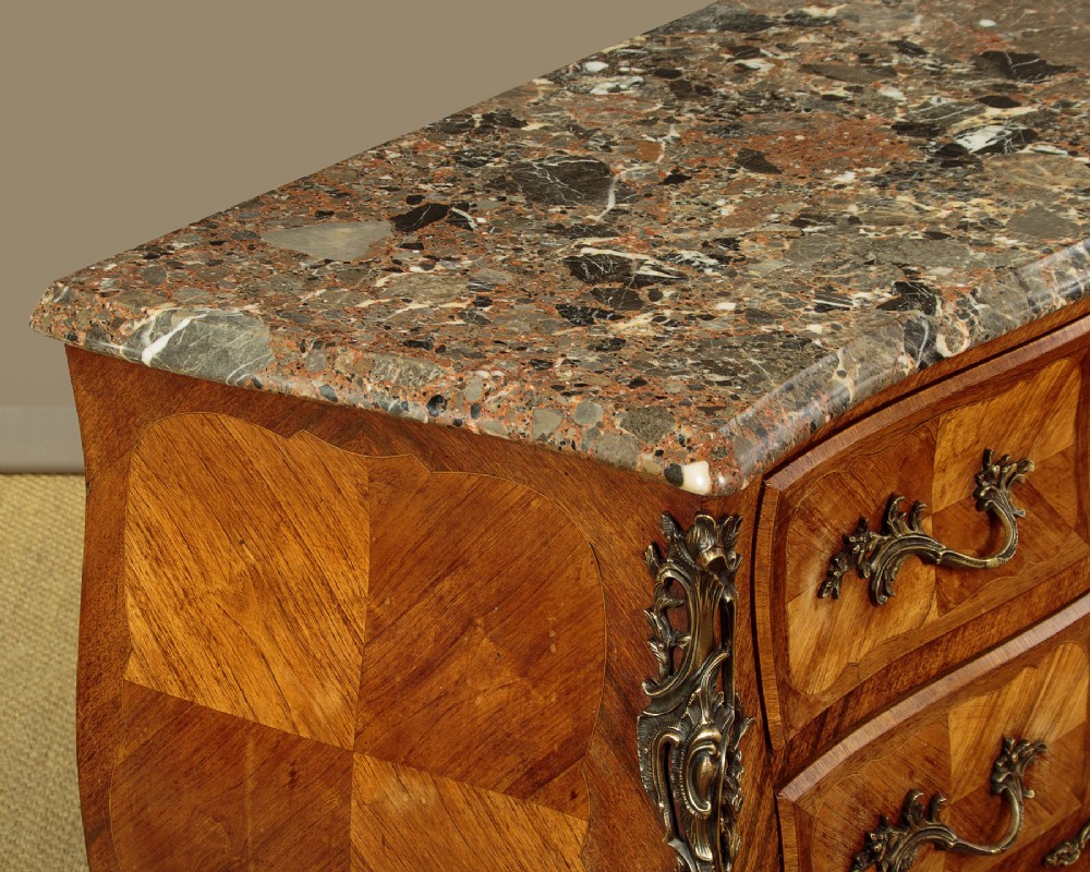 A 1930s Louis XV style bombe commode featuring a variegated grey marble top, parquetry wood veneer drawers, and ornate brass mounts. View VI