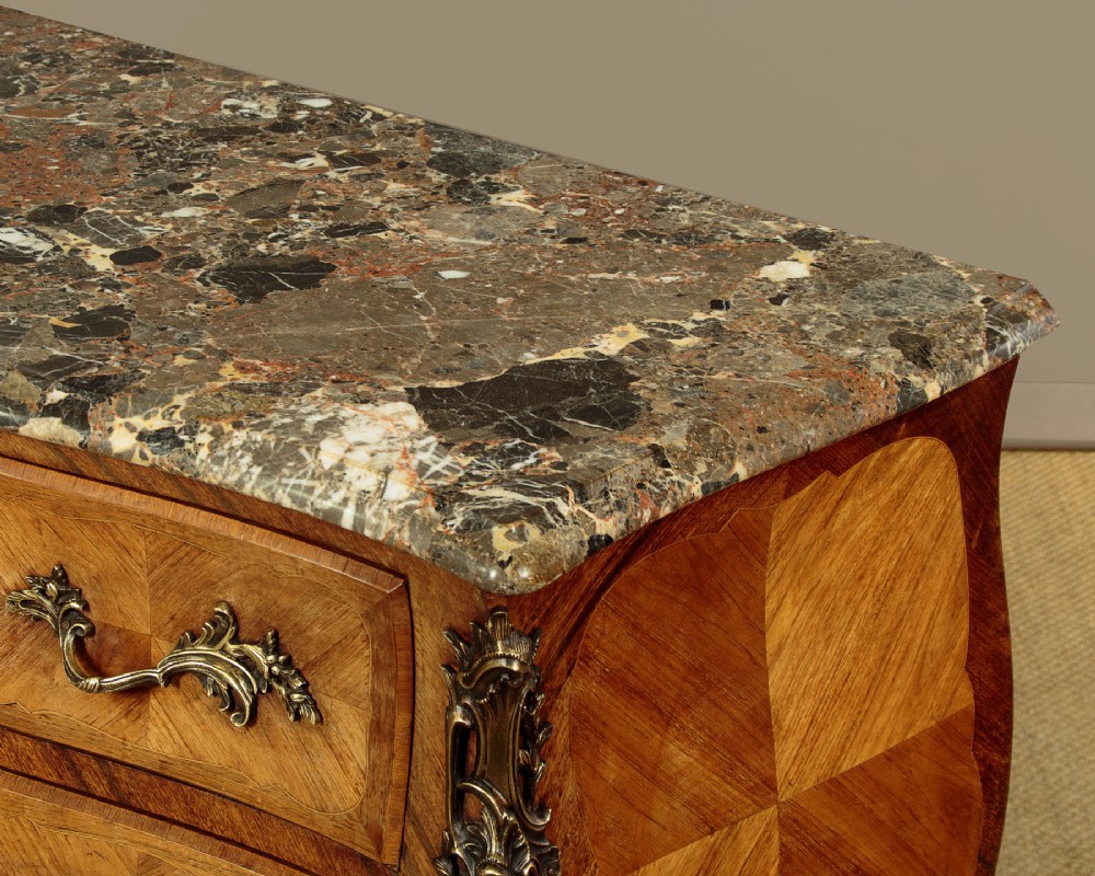 A 1930s Louis XV style bombe commode featuring a variegated grey marble top, parquetry wood veneer drawers, and ornate brass mounts. View VII