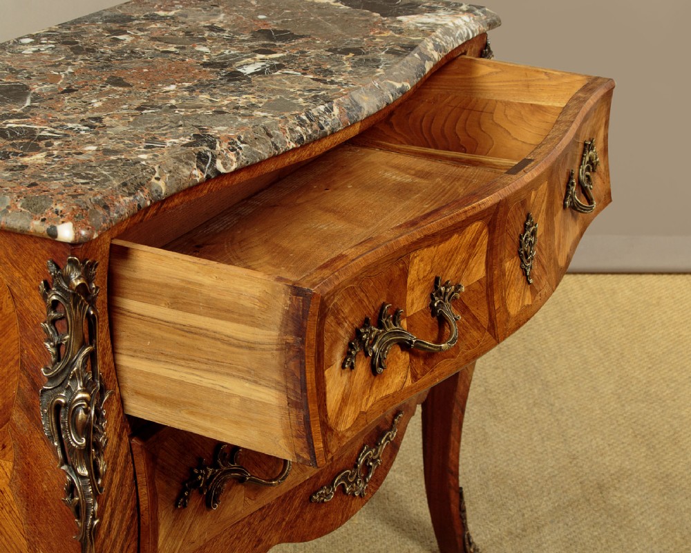 A 1930s Louis XV style bombe commode featuring a variegated grey marble top, parquetry wood veneer drawers, and ornate brass mounts. View VIII