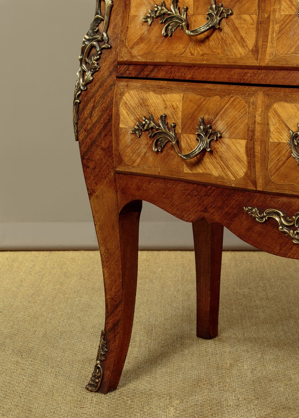 A 1930s Louis XV style bombe commode featuring a variegated grey marble top, parquetry wood veneer drawers, and ornate brass mounts. View XI